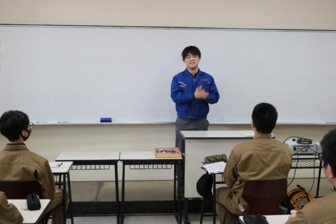 修了生が教壇に立って説明をしている写真